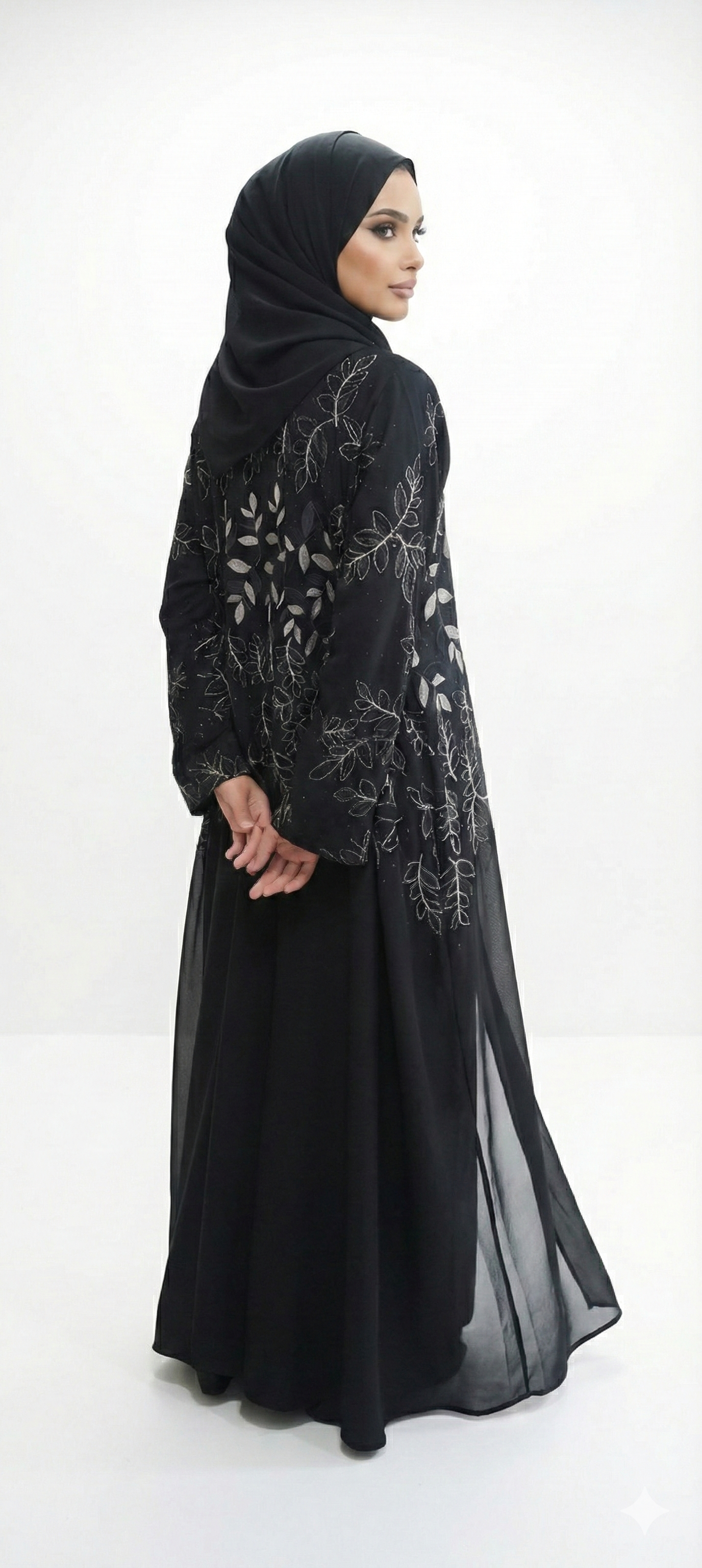 Back/side view of black abaya with gold leaf embroidery and black leaf detailing, model turning slightly to show the design.