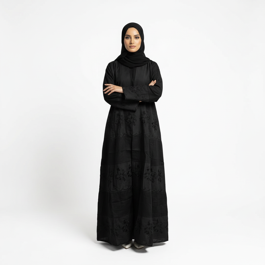Front arms-crossed pose wearing black Hana layered crepe abaya with understated floral embroidery, matching black hijab.